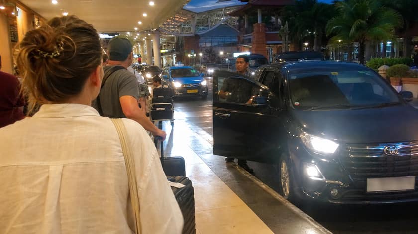 Travelers waiting with luggage at the Bali airport pickup area