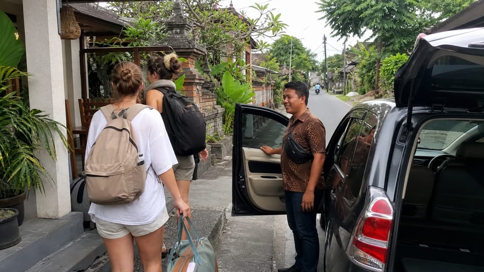 A private driver waiting beside a car at a Bali pickup point