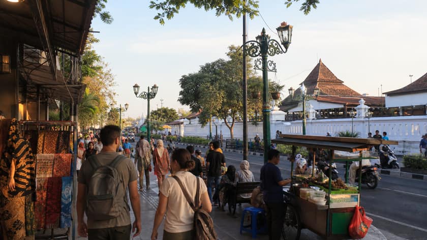 A Yogyakarta street scene with batik stalls, food carts and people walking