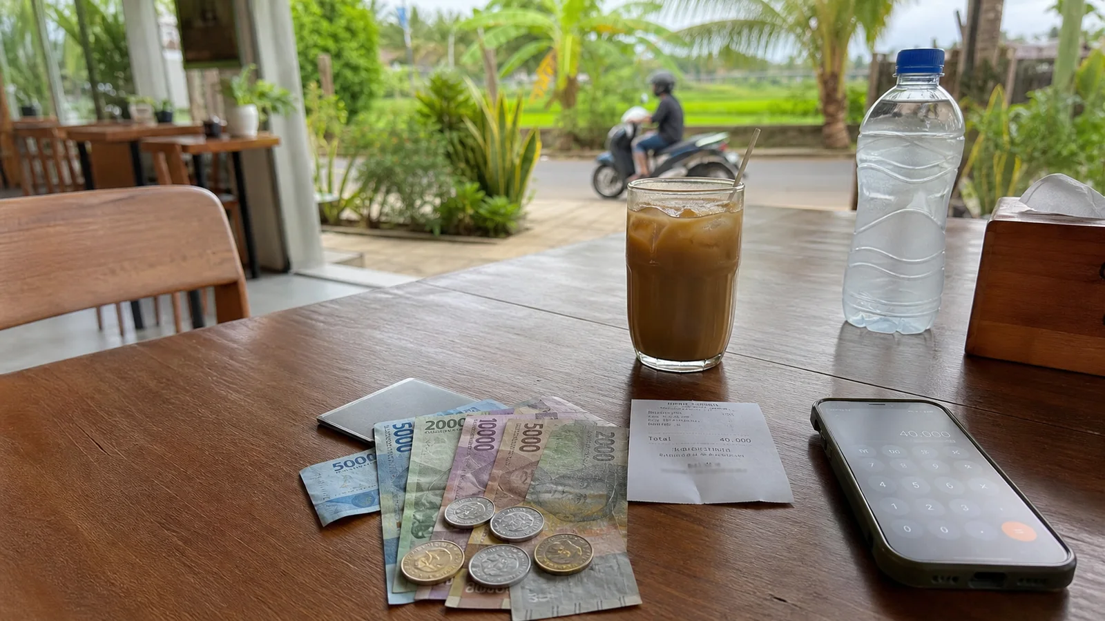 Indonesian rupiah, a receipt and a phone on a Bali cafe table