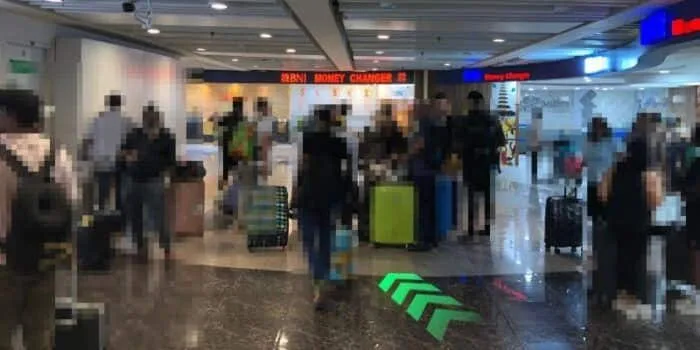 Grab official DPS image showing the money changer area after international baggage claim at Bali Airport.
