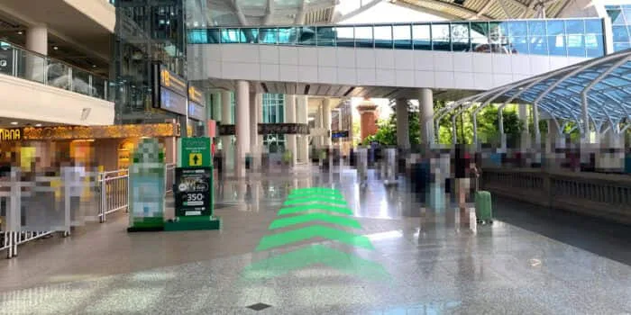 Grab official DPS image showing the international arrivals route past a Grab totem at Bali Airport.