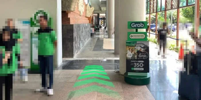 Grab official DPS image showing the outdoor route toward the Grab Lounge at Bali Airport.
